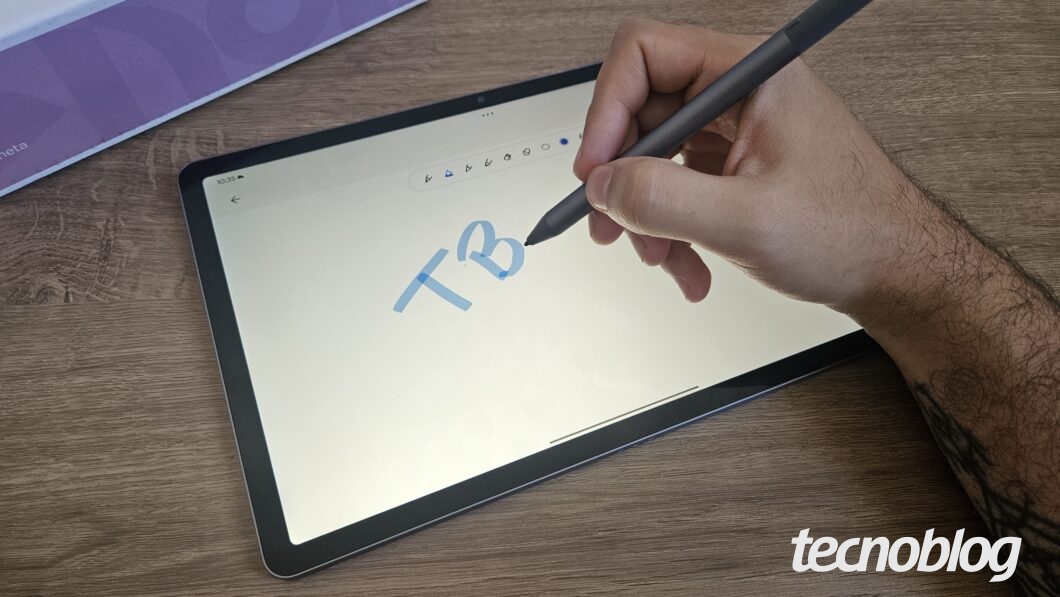 Uma mão segurando a caneta da Lenovo que acompanha o Lenovo Idea Tab escrevendo sobre a tela.