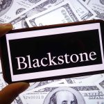 Logo da Blackstone em um smartphone; atrás, várias notas de dólar