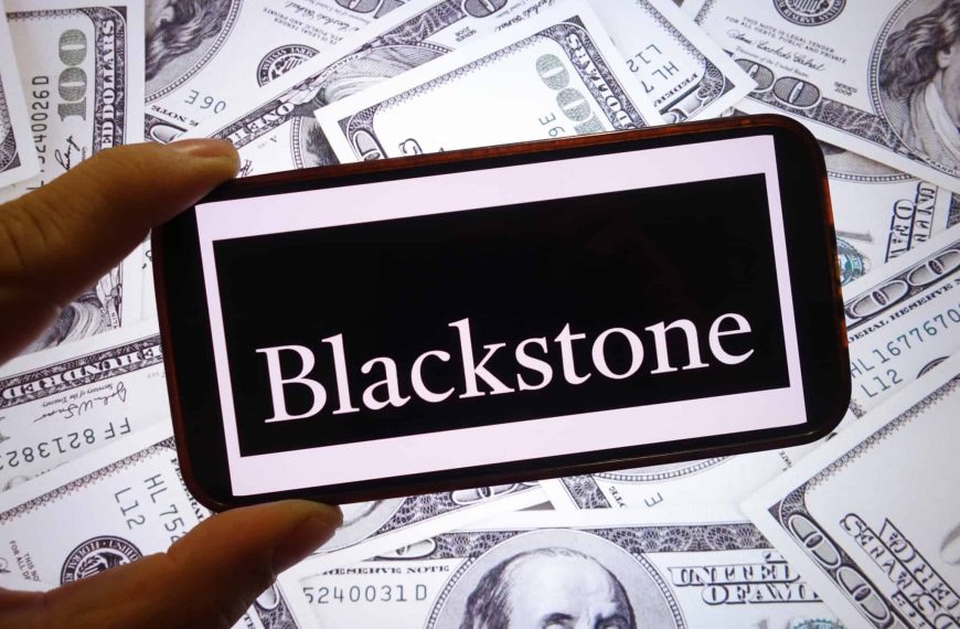 Logo da Blackstone em um smartphone; atrás, várias notas de dólar