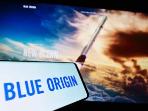 Logo da Blue Origin em um smartphone ao lado de uma imagem de um foguete
