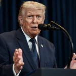 Donald Trump em um púlpito com as mãos abertas e falando em um microfone