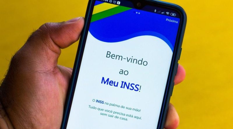 Pessoa segurando celular com aplicativo Meu INSS aberto na tela inicial