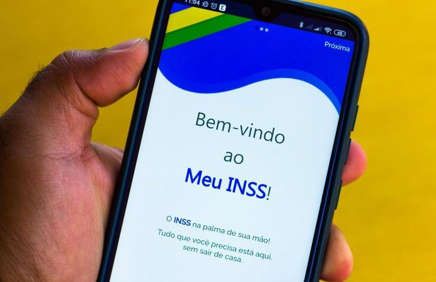 Pessoa segurando celular com aplicativo Meu INSS aberto na tela inicial