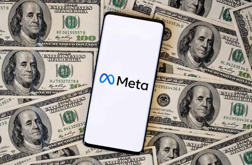 Logo da Meta em um smartphone, que está em cima de várias notas de dólares dos Estados Unidos